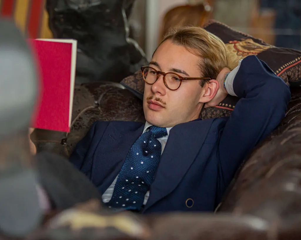 Tobin Gattinger mit Brille und grüner Carlo Fumeo Strickkrawatte liest ein Buch